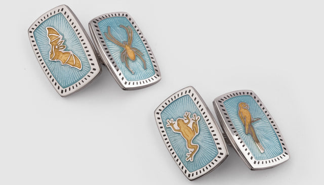 A final image of bespoke cufflinks with light blue enamel and animals engraved on them.
